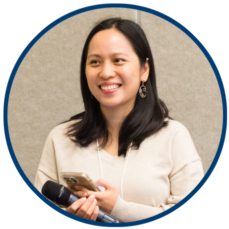 Alt text for headshot: a professional headshot of Gwen Nguyen, a woman with long black hair, wearing a beige sweater, smiling while holding a microphone and a smartphone at a conference